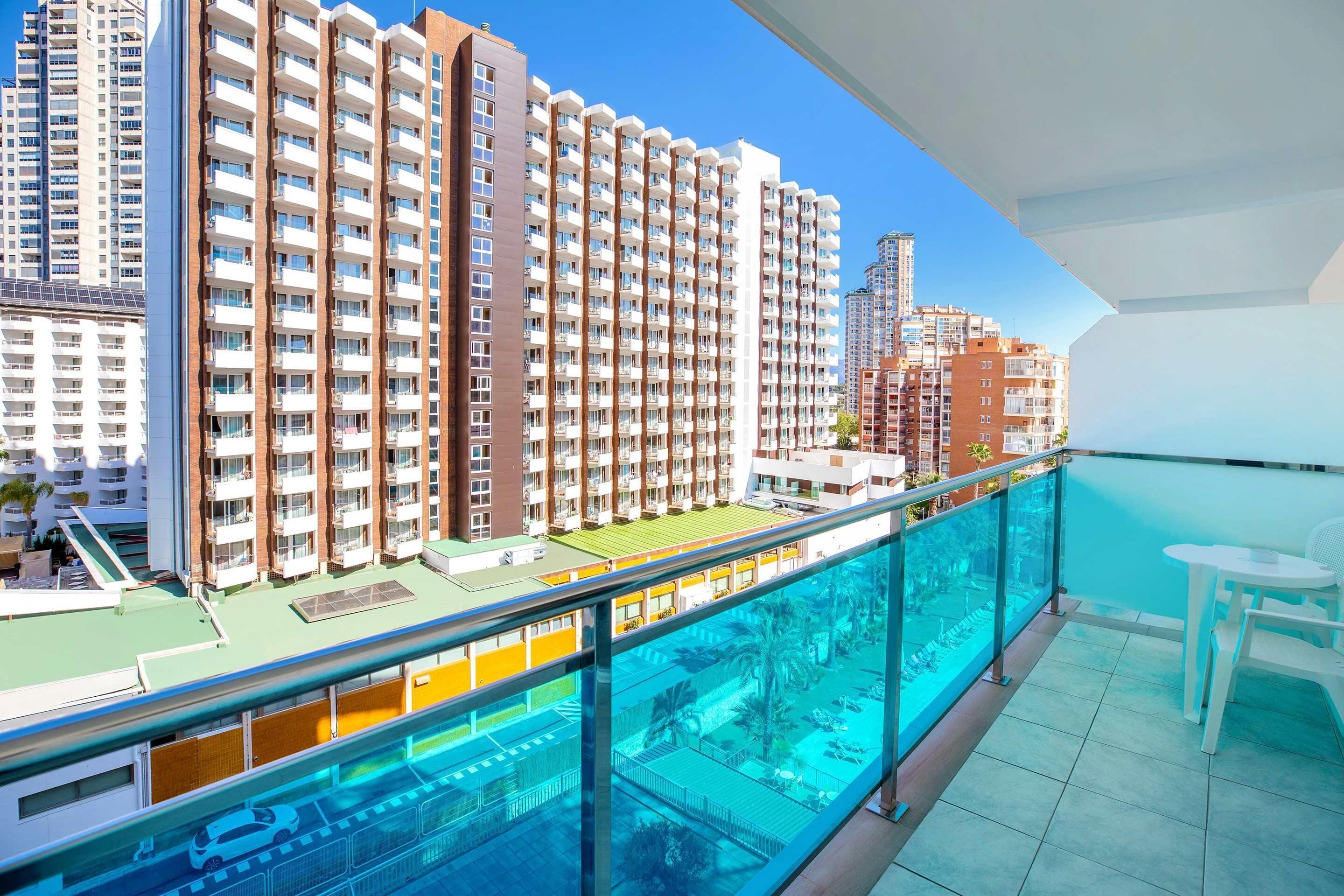 A high-rise residential building with multiple balconies, a swimming pool, and a clear view of the surrounding cityscape.