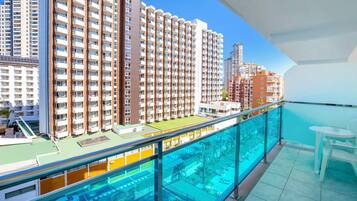 A high-rise residential building with multiple balconies, a swimming pool, and a clear view of the surrounding cityscape.