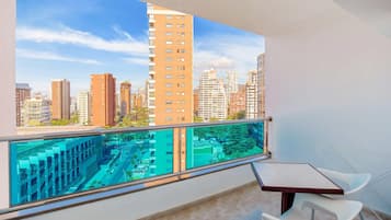 Un balcón con vistas a la ciudad, una mesa y dos sillas.