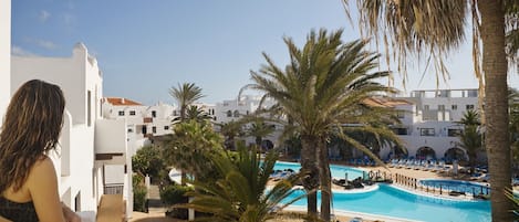 A resort with a pool area, palm trees, and white buildings.