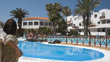 Relax by the resort pool surrounded by palm trees and a picturesque building.