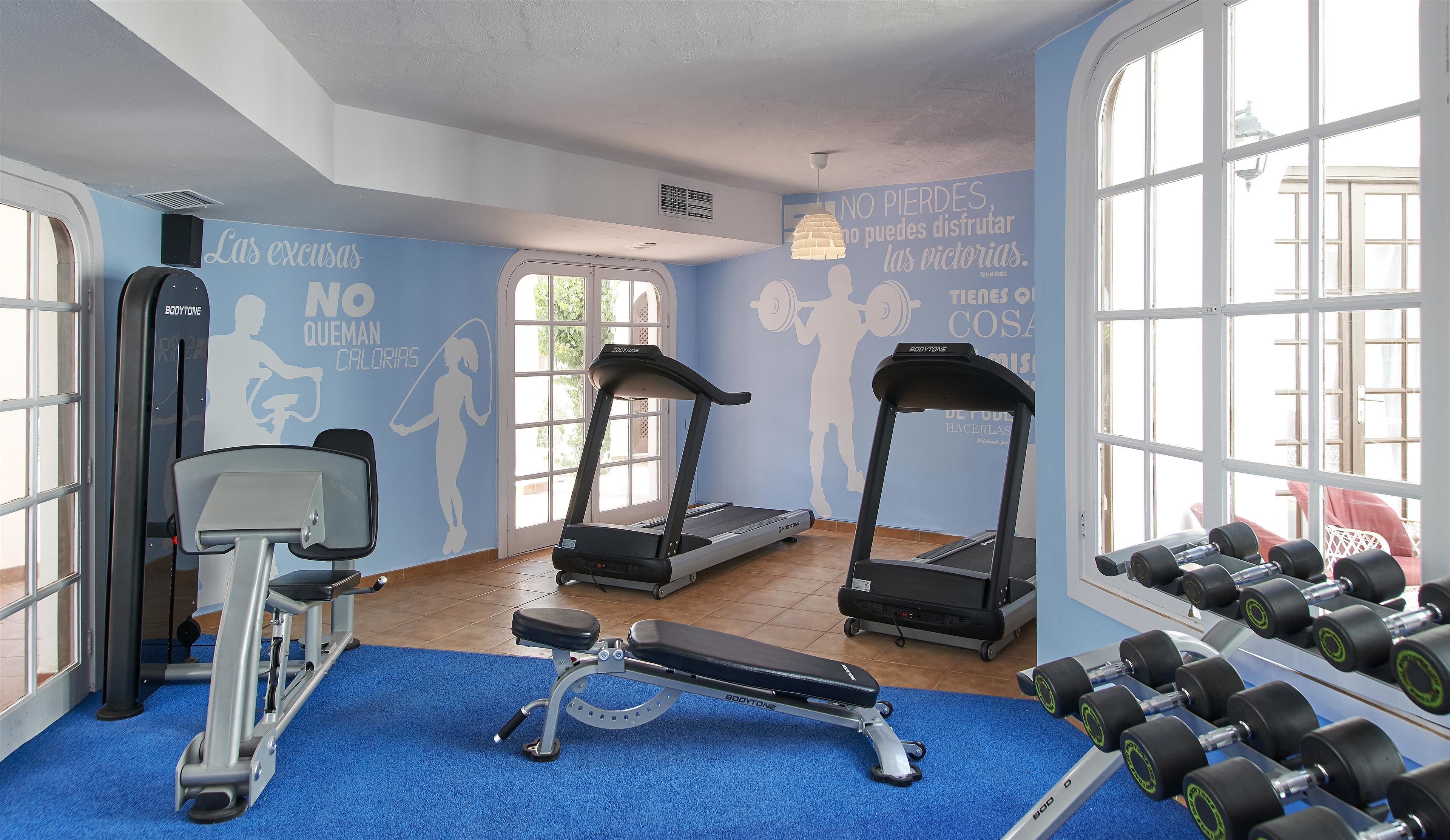 A gym with treadmills, a bench press, and dumbbells.