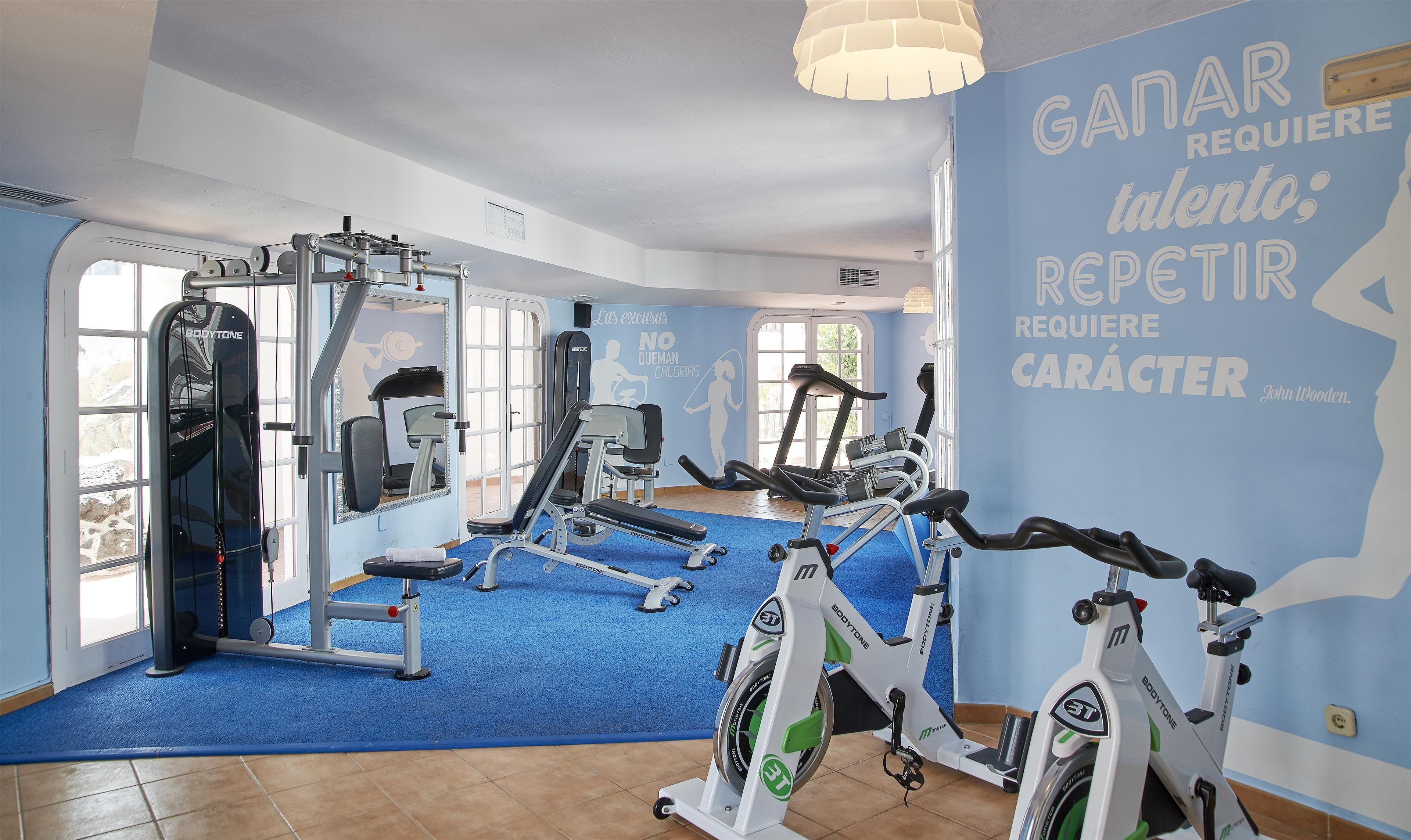 A gym with cardio machines, weight equipment, and motivational wall art.