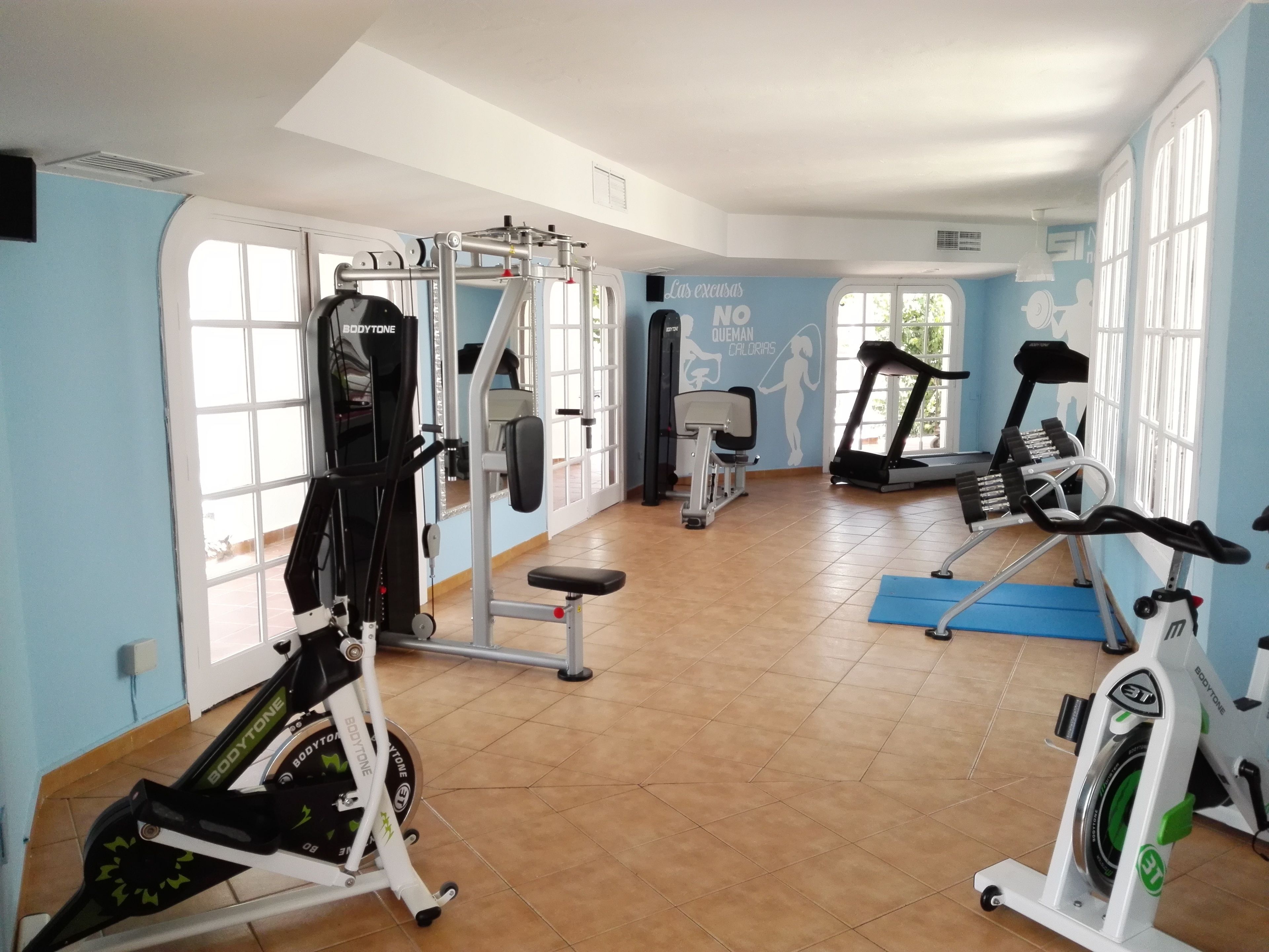 Ein Fitnessraum mit Cardiogeräten, Krafttrainingsgeräten und einer Wand mit motivierenden Texten.