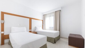 A hotel room with two beds, a wooden headboard, a brown ottoman, and a window with curtains. - Apartamentos Hesperia Bristol Playa (La Oliva)