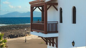 A coastal building with a balcony overlooking the sea, featuring a simple architectural design and a clear view of the ocean and distant mountains. - Apartamentos Hesperia Bristol Playa (La Oliva)