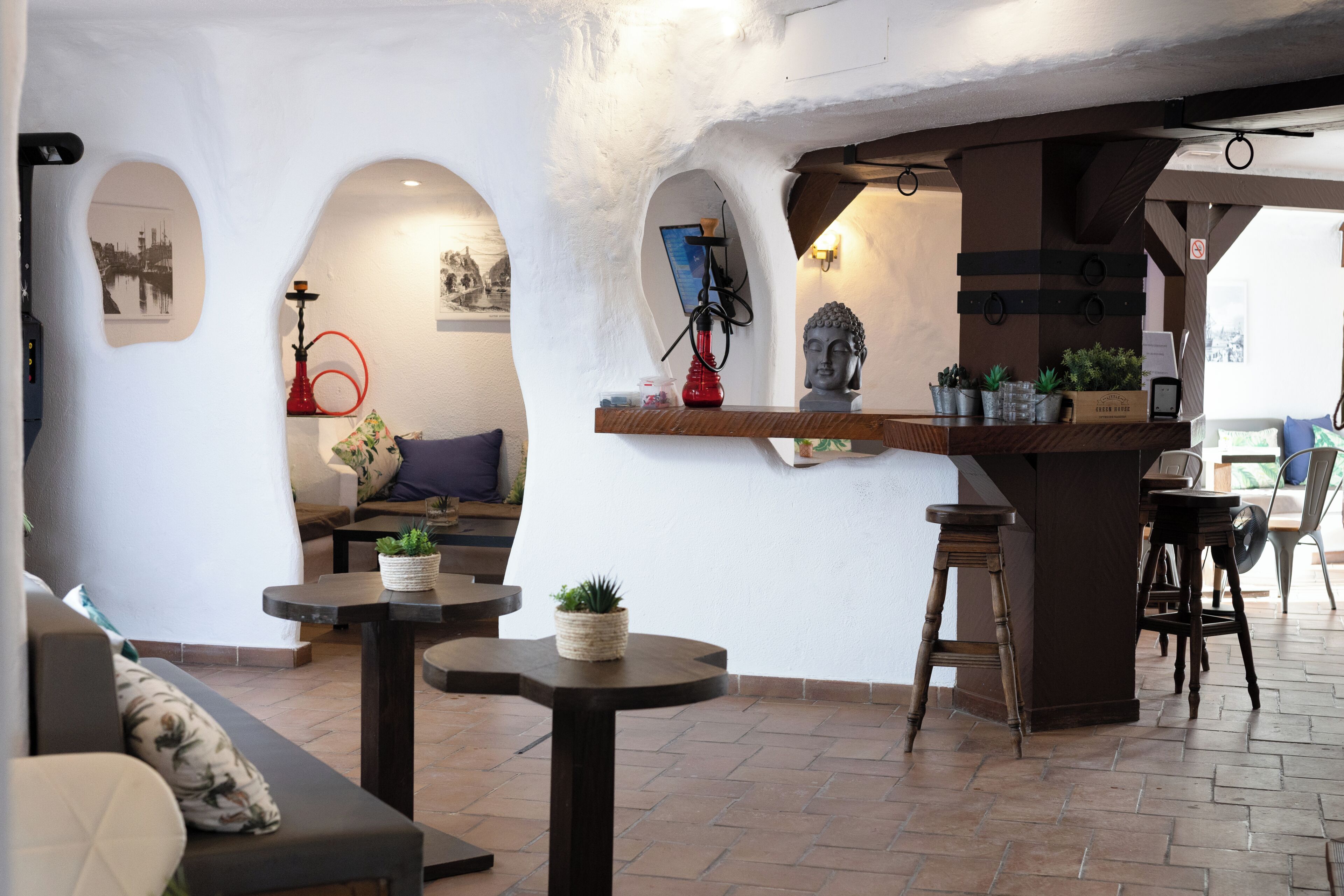 Un ambiente acogedor con una zona de bar, asientos y plantas decorativas.