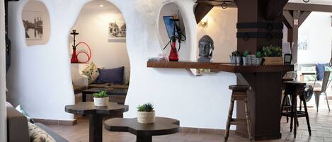 Un ambiente acogedor con una zona de bar, asientos y plantas decorativas.