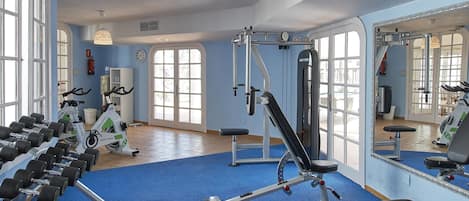 A gym with exercise equipment, a blue carpet, and large windows.