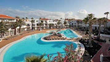 Ein Resort mit einem großen Schwimmbad, Liegestühlen und Palmen.