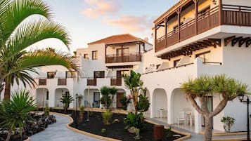 A courtyard with white buildings, balconies, and tropical plants.