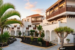 A courtyard with white buildings, balconies, and tropical plants.