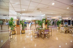 A spacious lobby with a polished marble floor, several tables and chairs, and potted plants. - Hotel Servigroup Diplomatic (Benidorm)