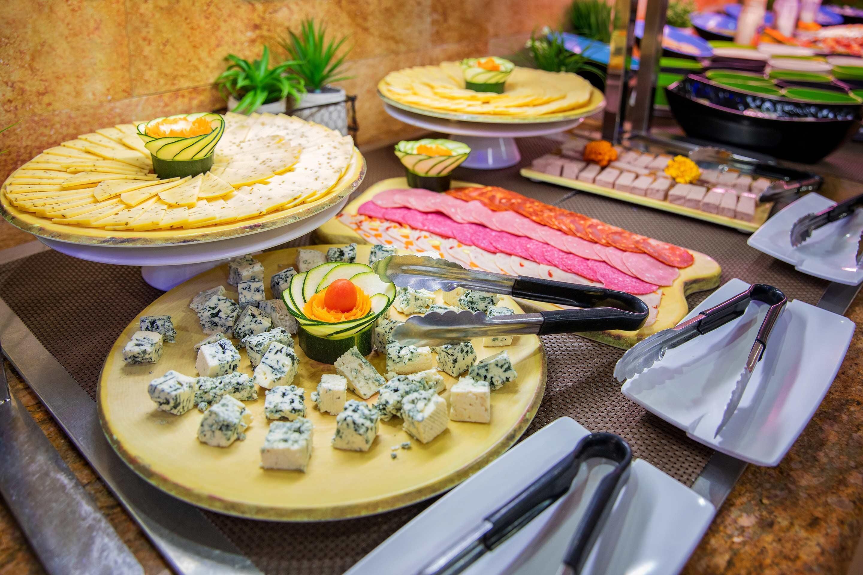 A buffet with various food items including cheese, meats, and vegetables.