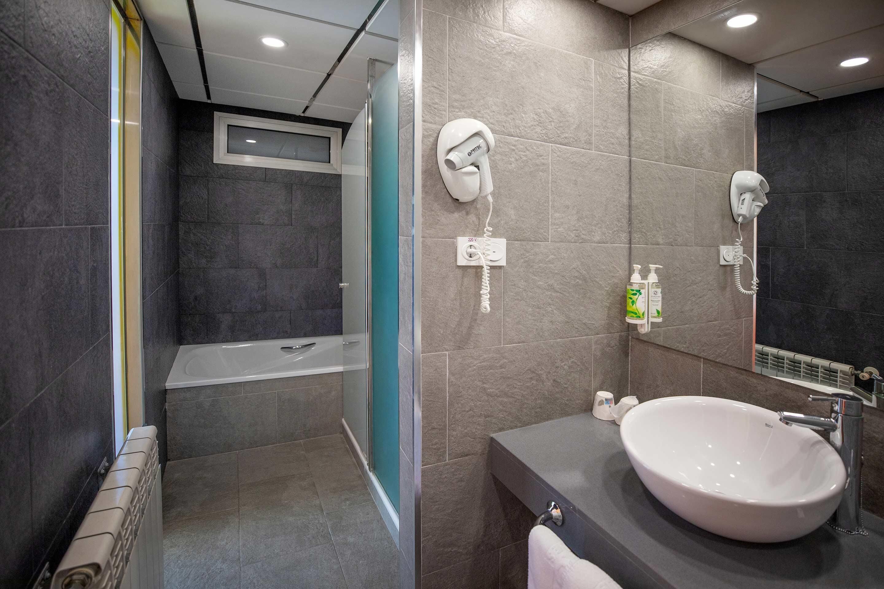 Une salle de bain moderne équipée d’un grand lavabo, d’un sèche-cheveux et d’une douche.