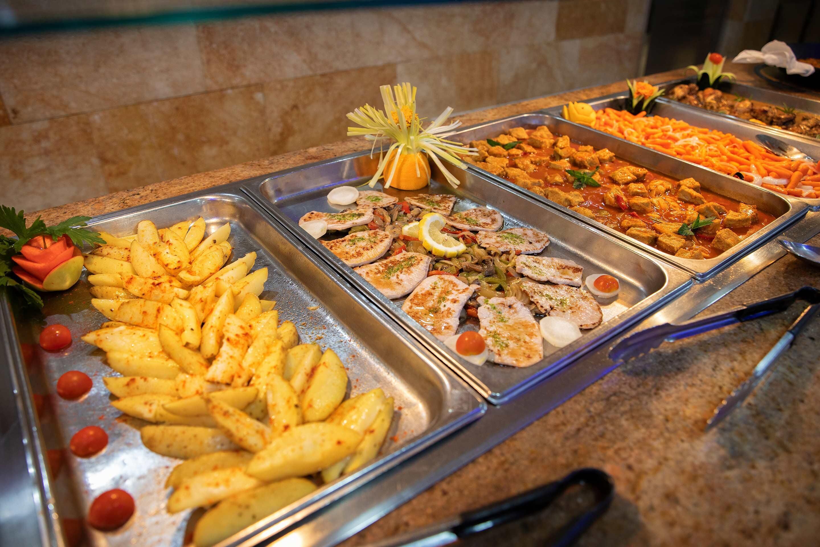 A buffet with various dishes including potatoes, chicken, and vegetables.