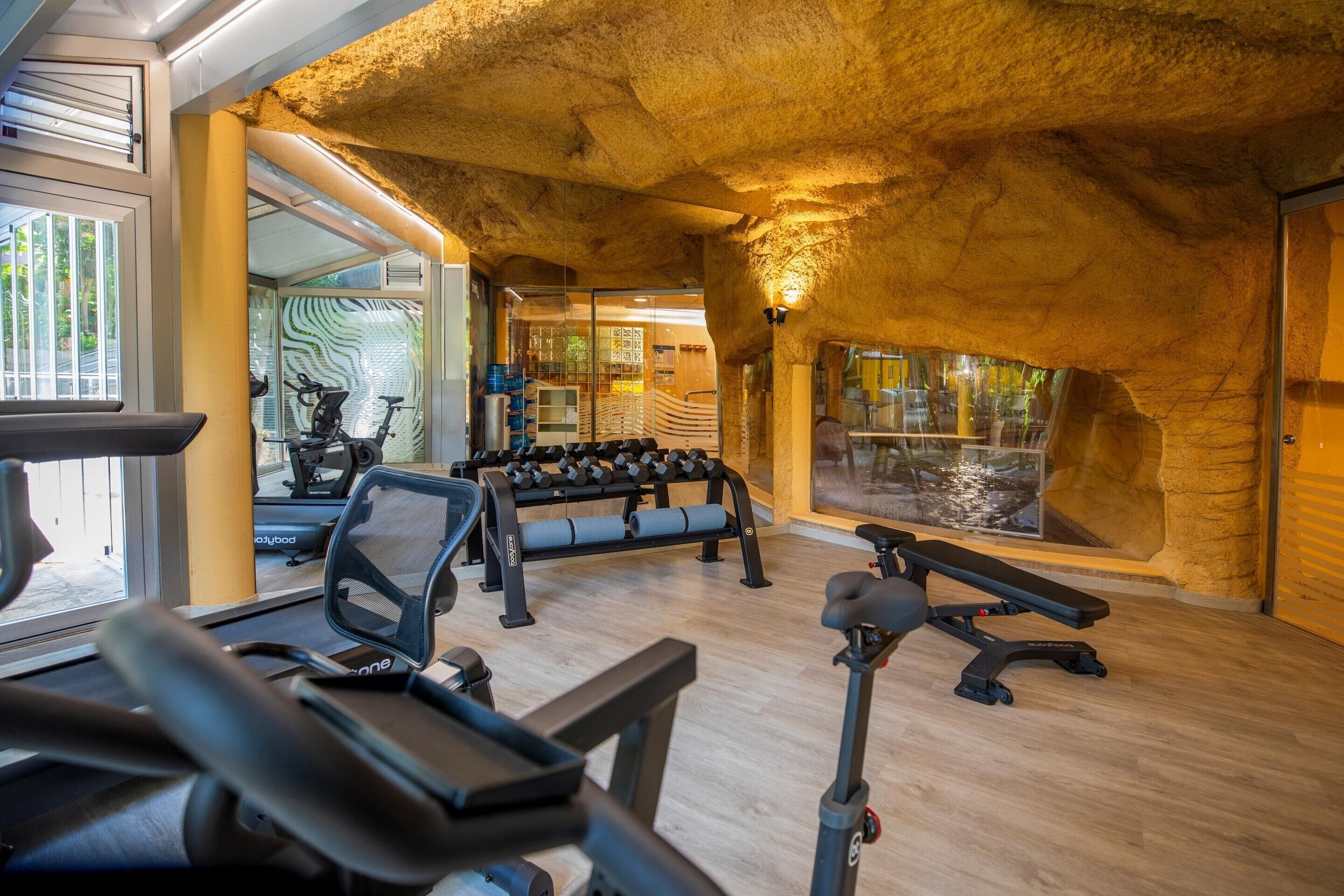 A gym with exercise equipment, a treadmill, and a wall-mounted TV.