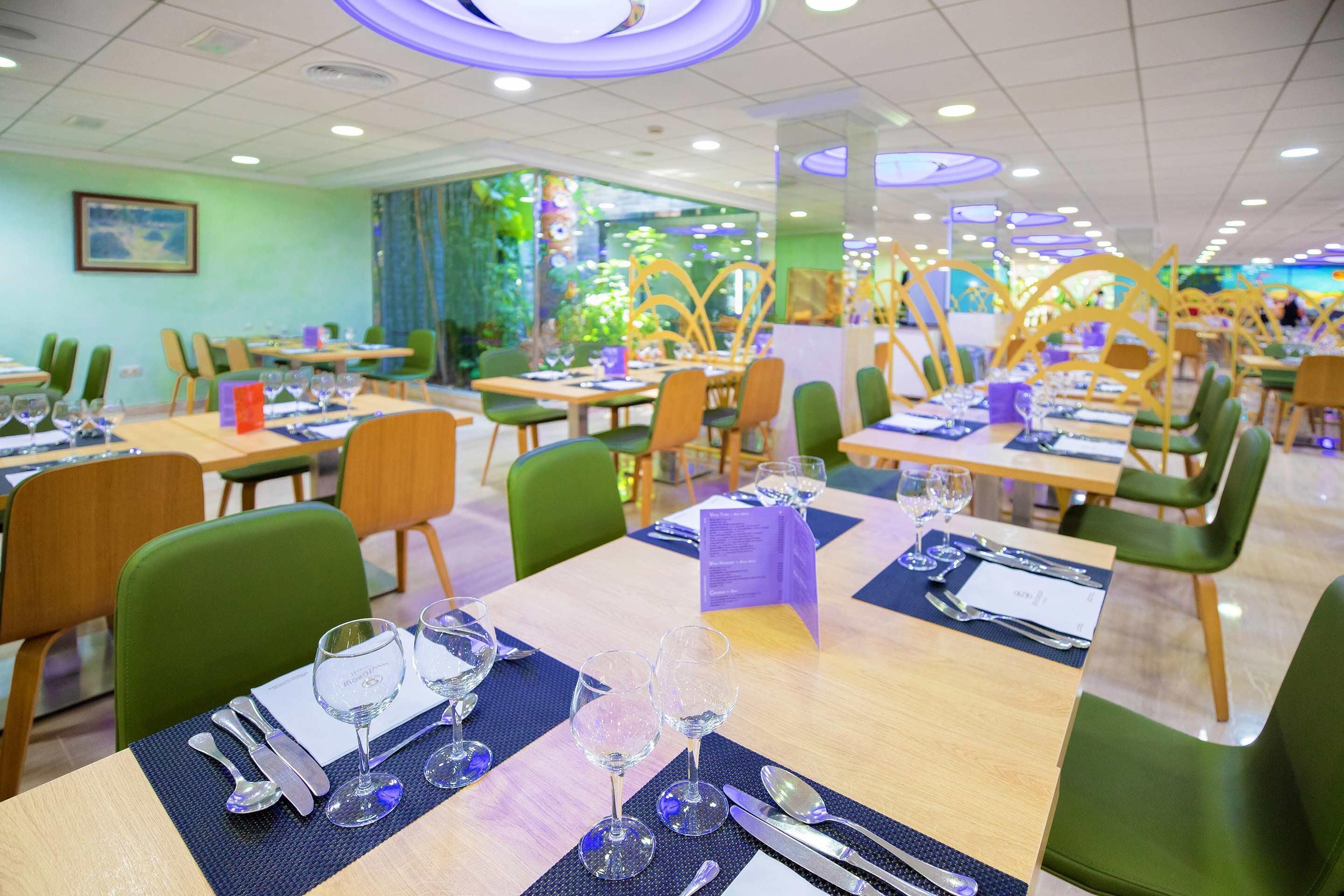 Un restaurante con varias mesas dispuestas para comer, cada una con cubiertos y vasos.