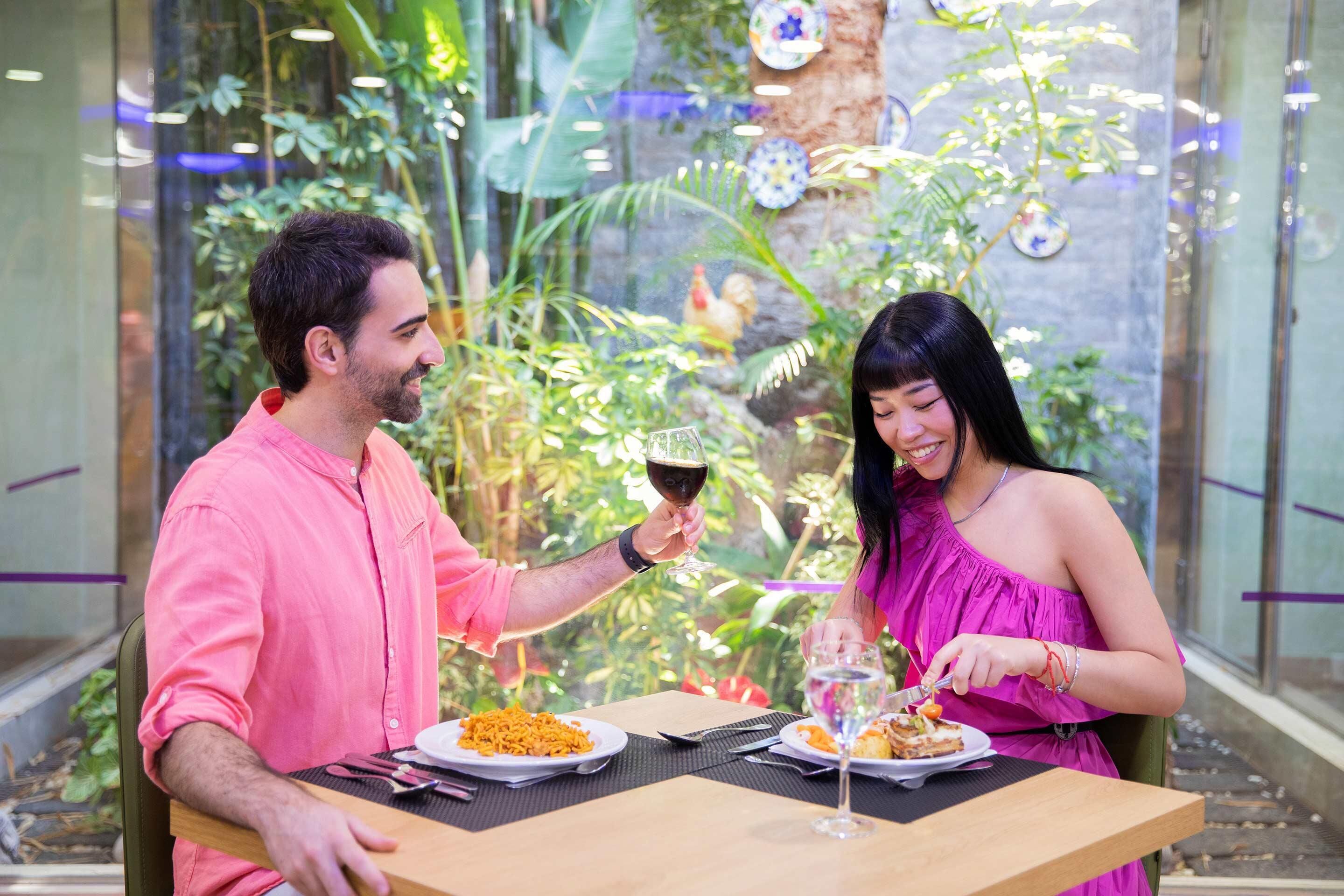 A couple dining at a table with a view of indoor greenery and decorative elements.