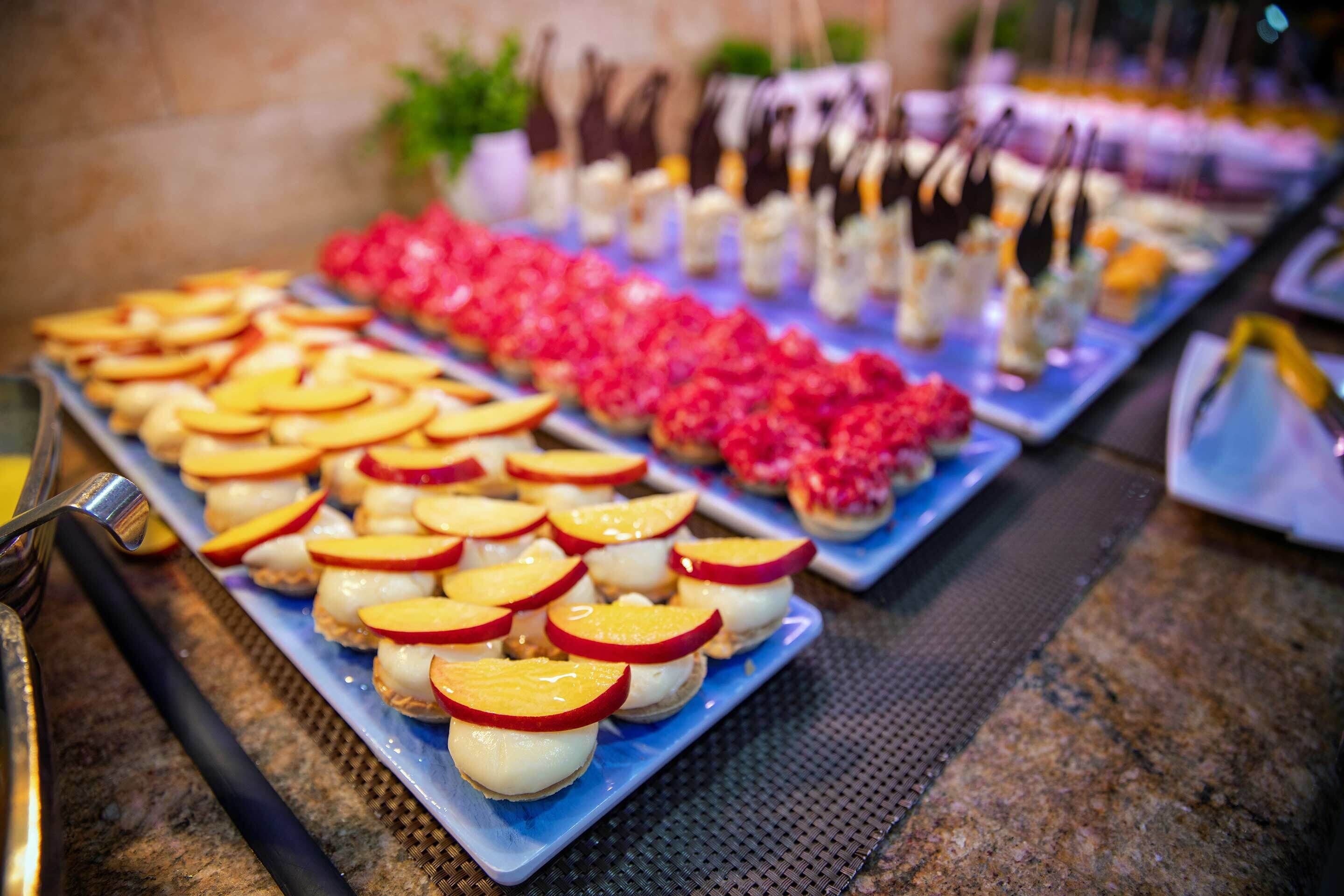 A buffet with various food items including fruit-topped desserts and chocolate-covered treats.