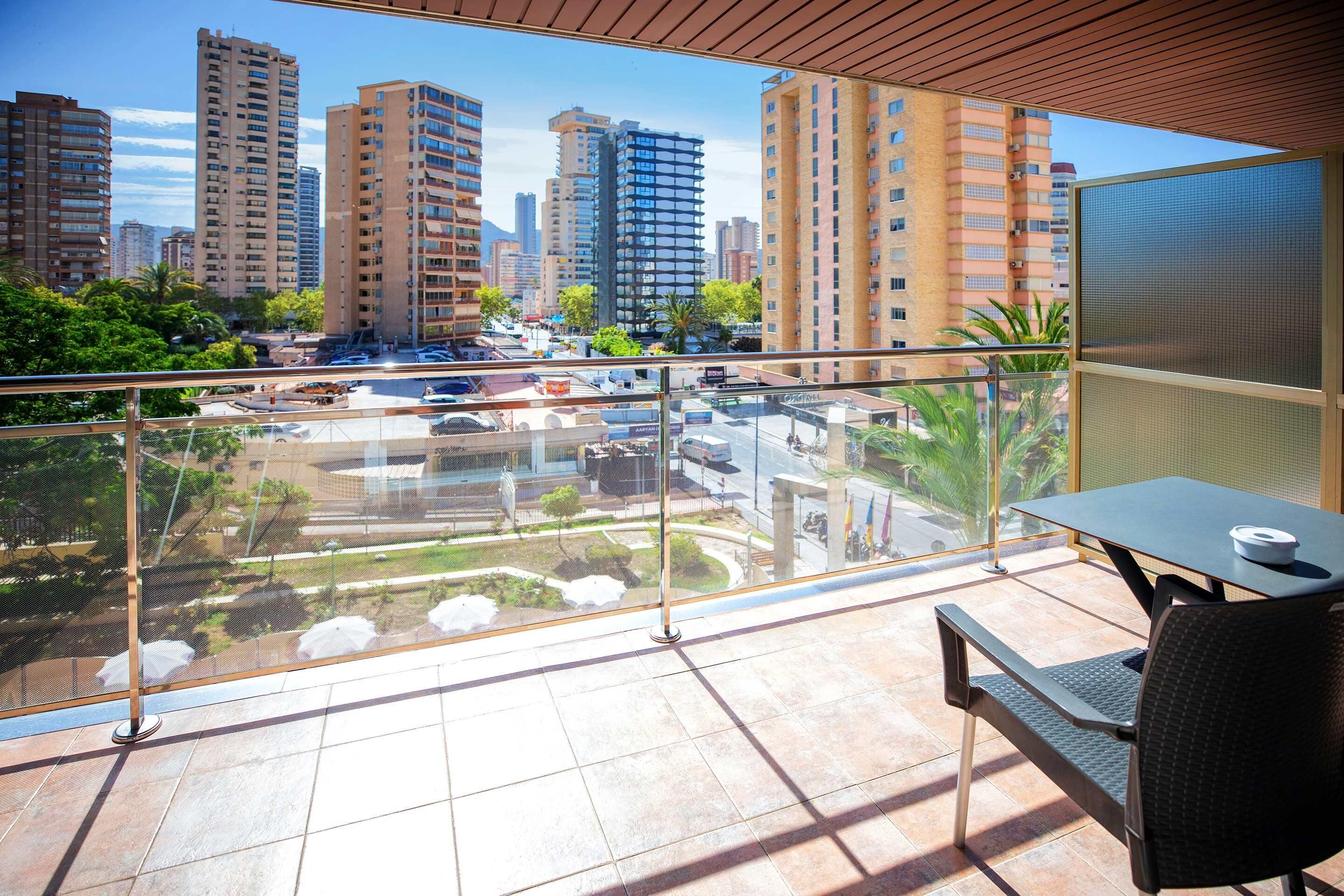 A balcony with a view of a cityscape, including tall buildings and a parking lot.