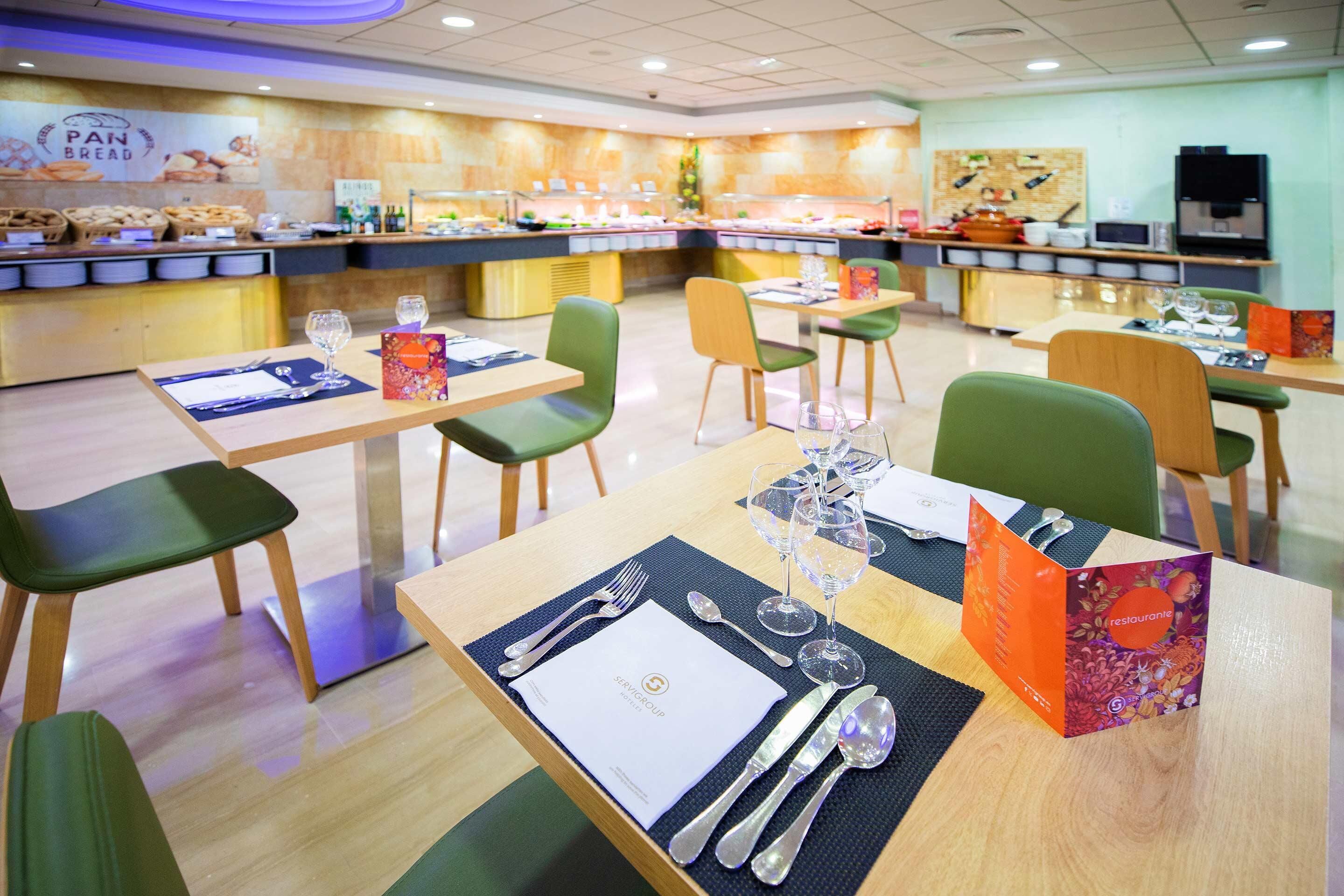 Um restaurante com várias mesas de jantar, cada uma posta com talheres, copos e cardápios.