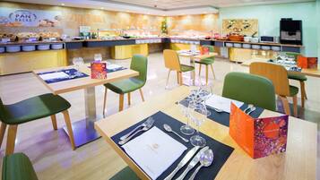 Um restaurante com várias mesas de jantar, cada uma posta com talheres, copos e cardápios.