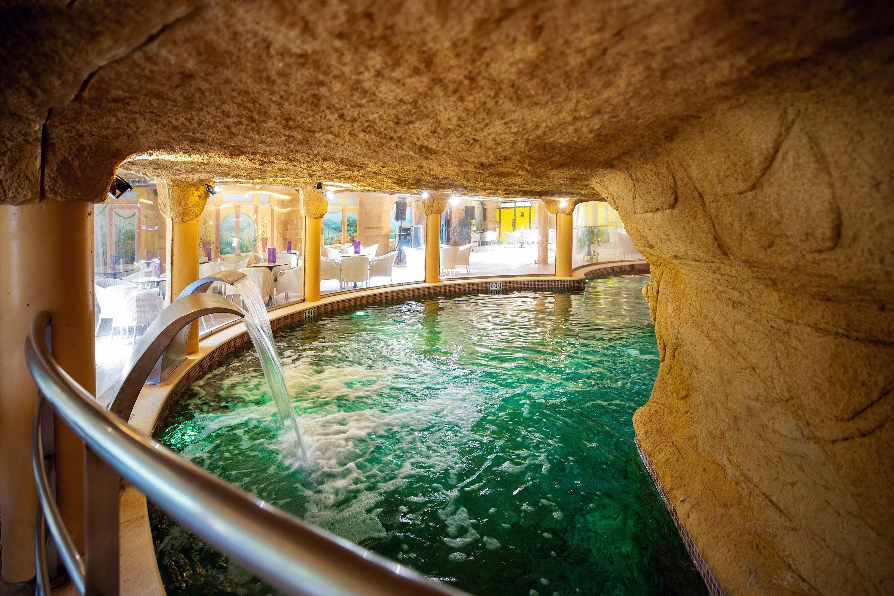 Un área de spa con hidromasaje, paredes de piedra y vistas al restaurante.