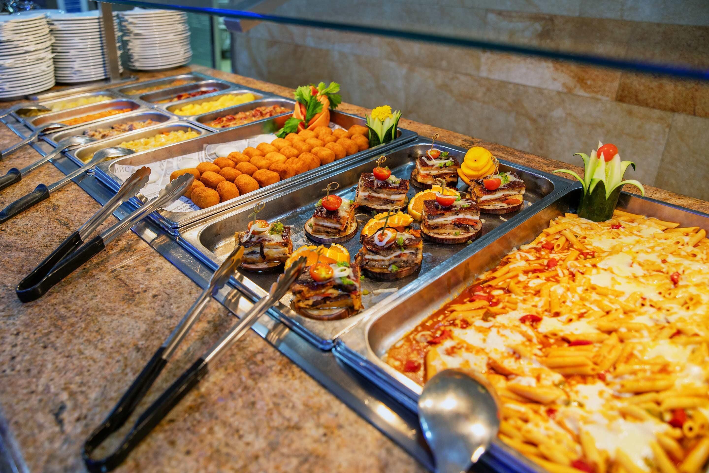 Un buffet con diverse opzioni tra cui pasta, piatti di carne e insalate.