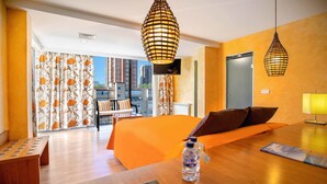 Une chambre d’hôtel équipée d’un lit, d’un bureau, d’un téléphone, d’une bouteille d’eau et d’un téléviseur.