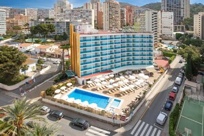 A hotel with a large pool area, multiple floors, and a cityscape in the background. - Hotel Servigroup Rialto (Benidorm)