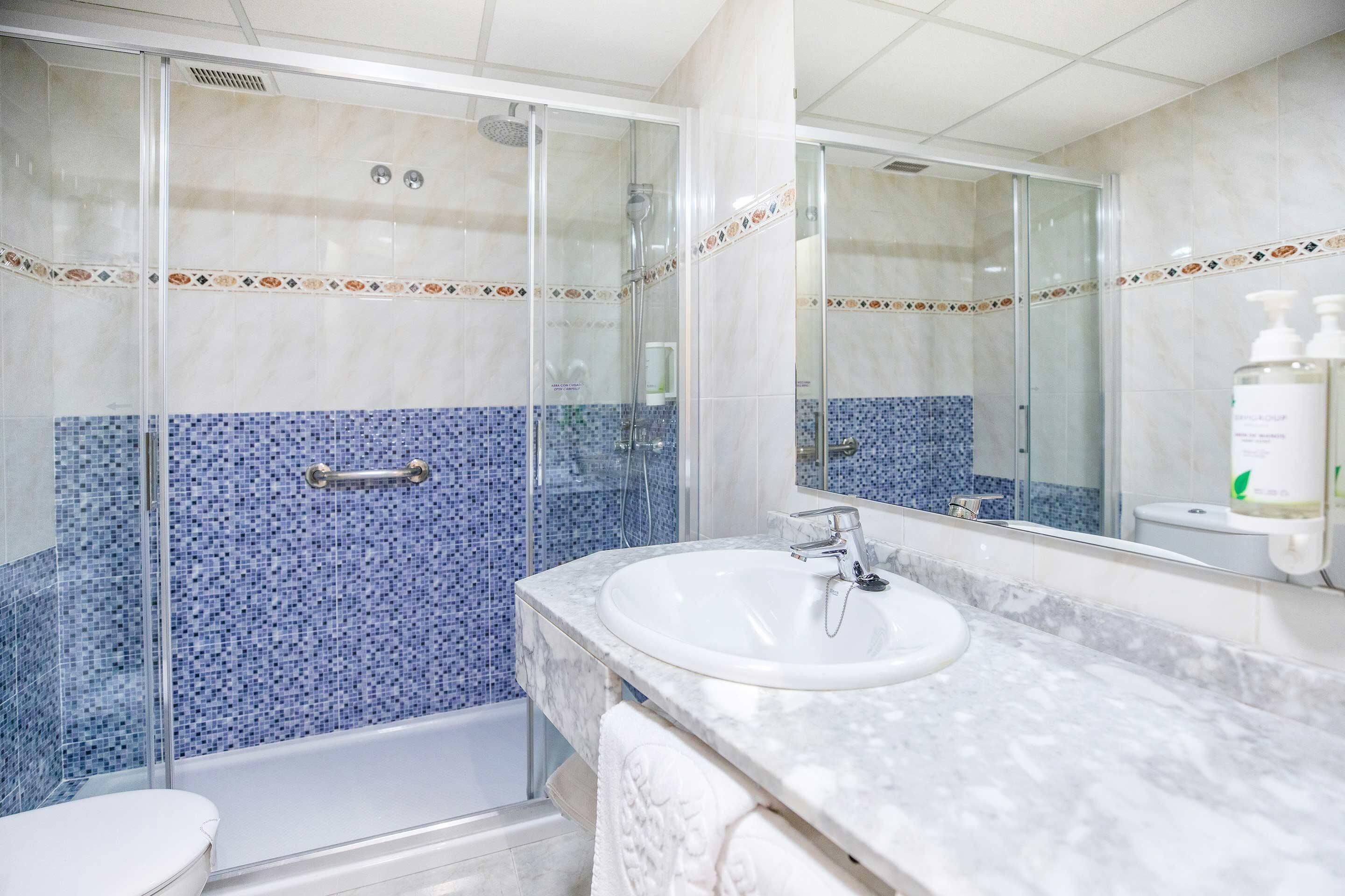A bathroom with a glass-enclosed shower, a white sink, and a tiled backsplash.