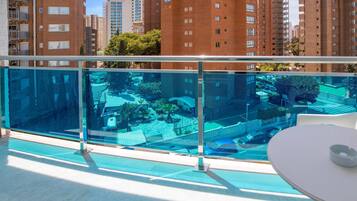 A modern apartment with a balcony overlooking a pool and a cityscape.