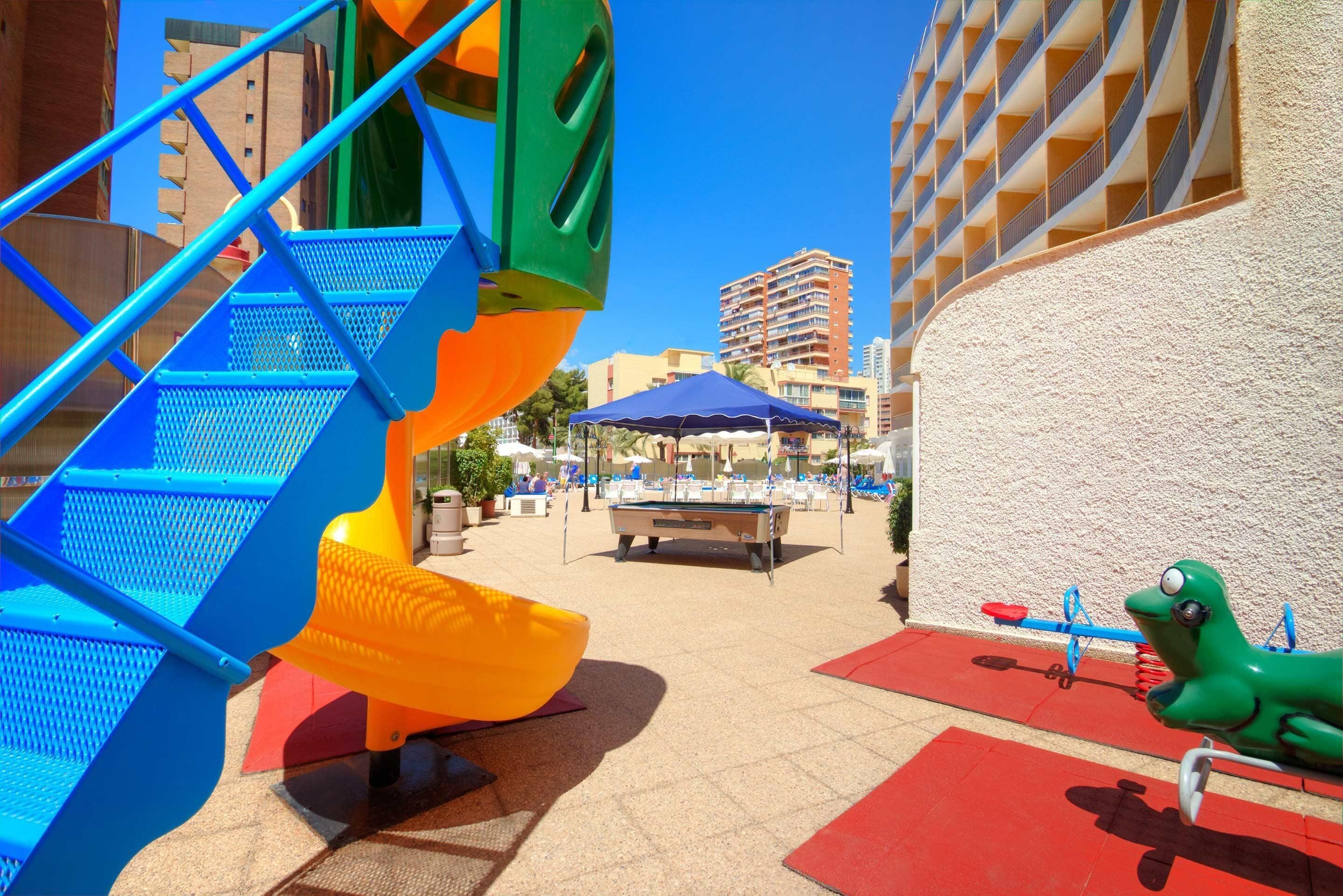 Zona infantil con tobogán, estructura de escalada y mesa de billar.