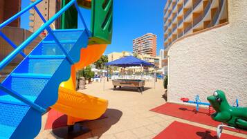 Zona infantil con tobogán, estructura de escalada y mesa de billar.