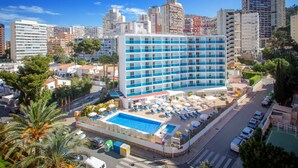 A hotel with a pool, multiple floors, and a cityscape in the background. - Hotel Servigroup Rialto (Benidorm)