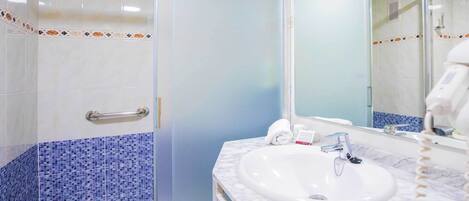 A bathroom with a white sink, a mirror, and a shower area.
