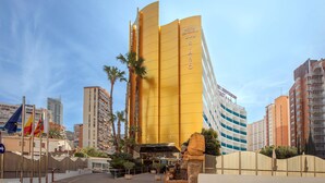 A hotel with a distinctive yellow facade, multiple floors, and a prominent entrance. - Hotel Servigroup Rialto (Benidorm)