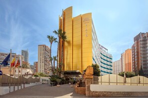 A hotel with a distinctive yellow facade, multiple floors, and a prominent entrance. - Hotel Servigroup Rialto (Benidorm)