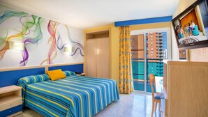 A hotel room with a bed, a desk, a chair, a wardrobe, a TV, and a balcony with a view of the city. - Hotel Servigroup Rialto (Benidorm)