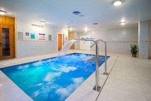 Una piscina con fuente, paredes de azulejos y una puerta de madera.