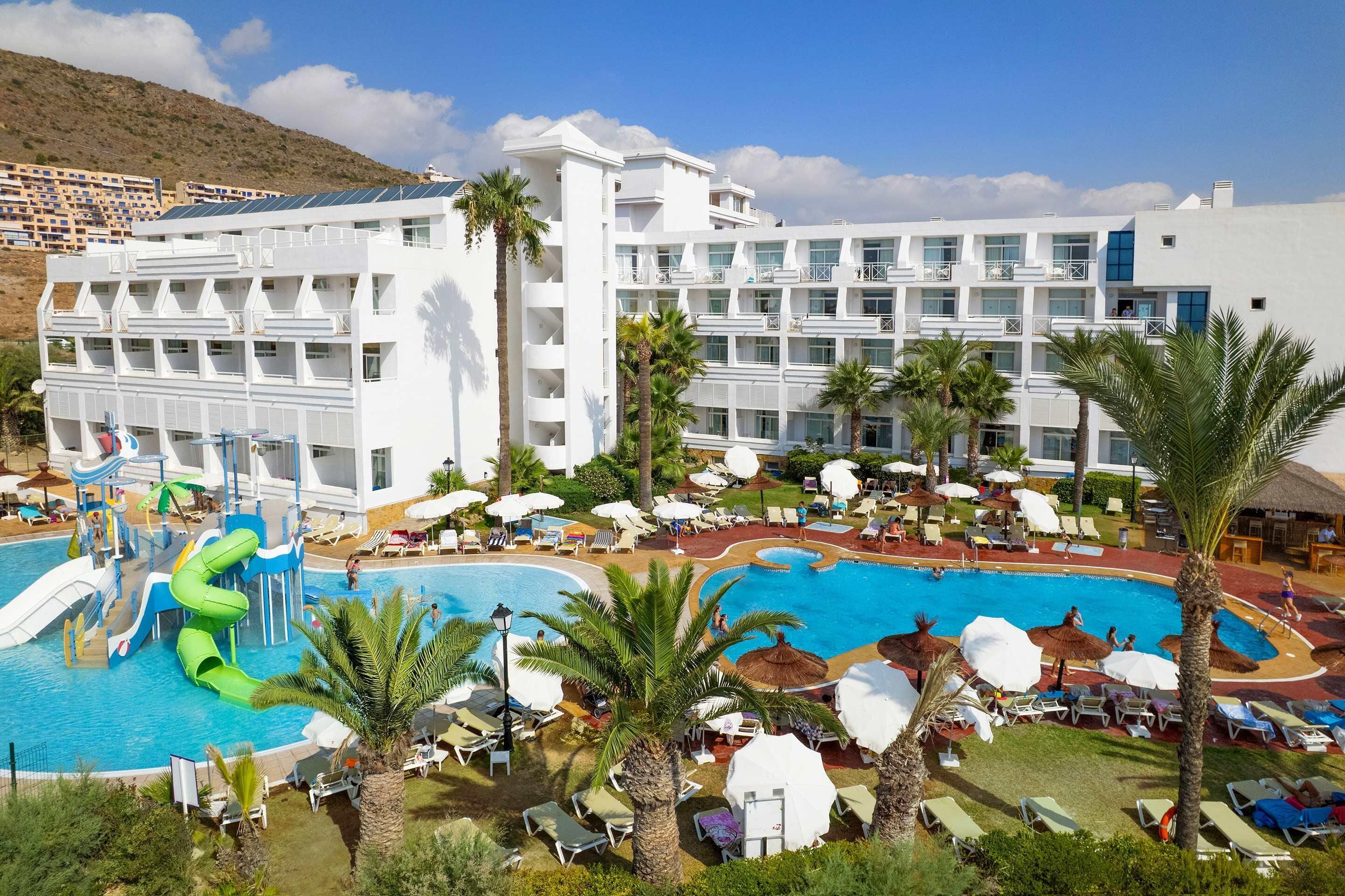 A resort with a large swimming pool, multiple balconies, and a water slide.