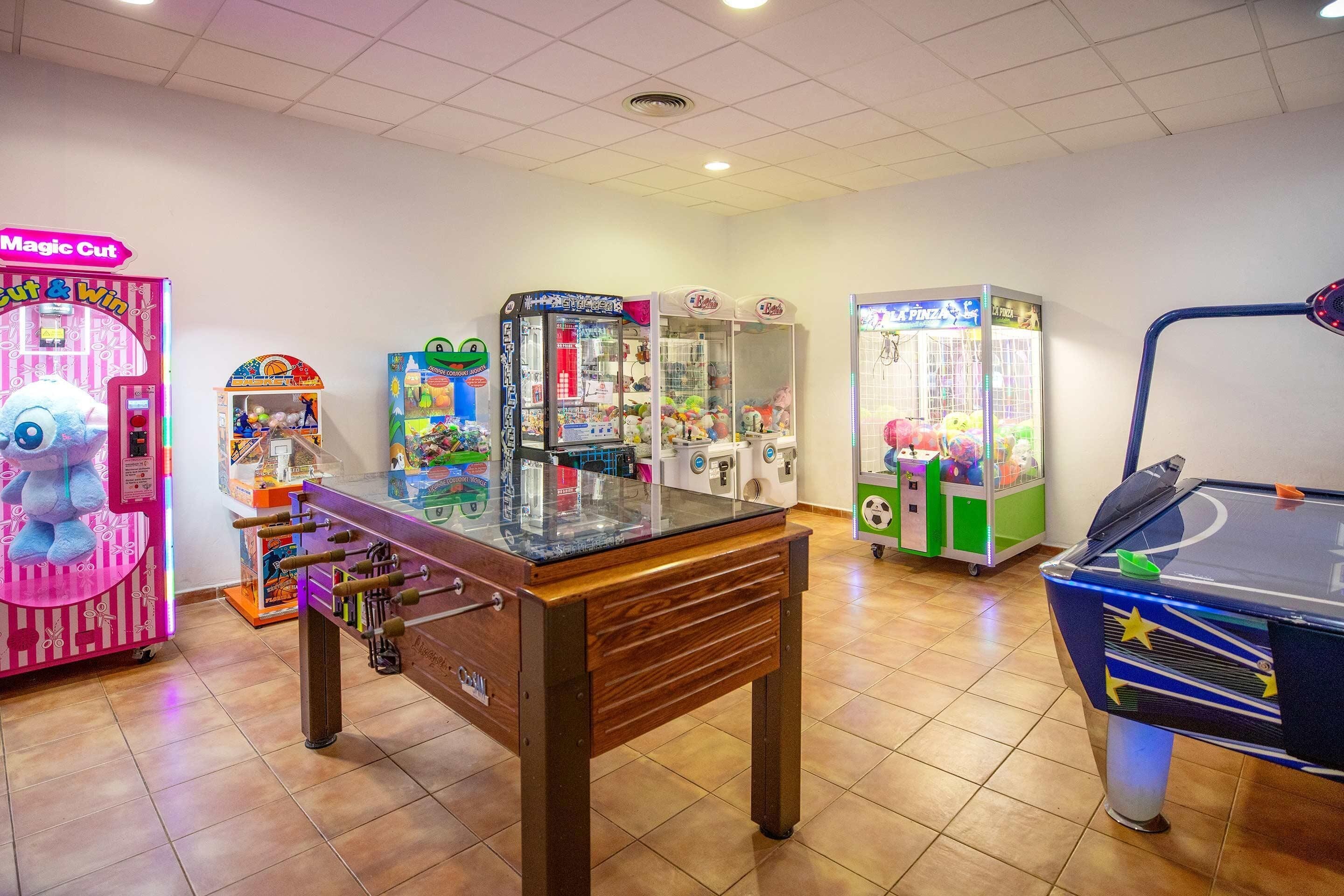 Una habitación con mesa de futbolín, varios juegos de arcade y mesa de billar.
