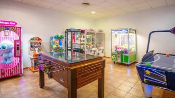Una habitación con mesa de futbolín, varios juegos de arcade y mesa de billar.