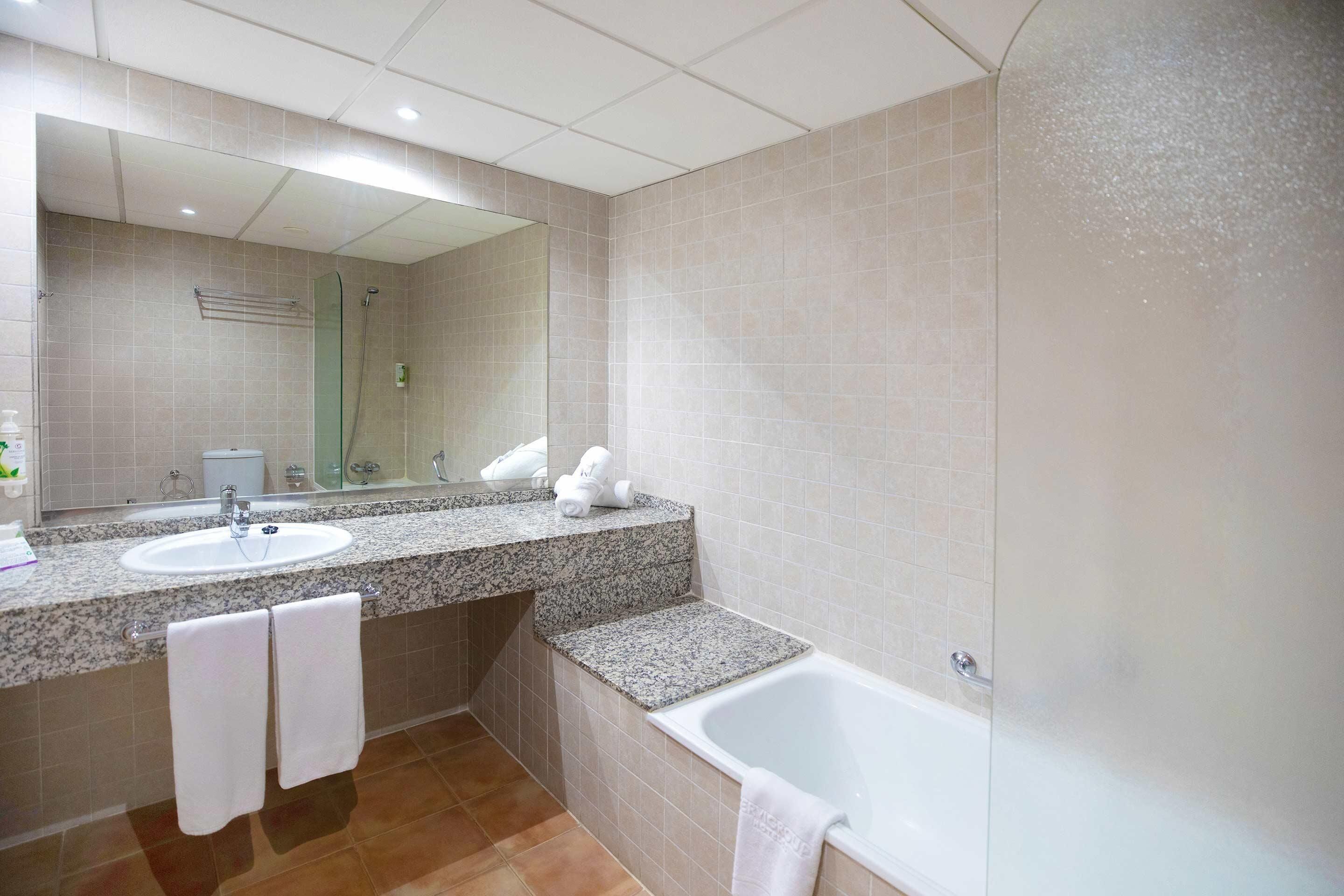 A modern bathroom with a sink, mirror, and bathtub.