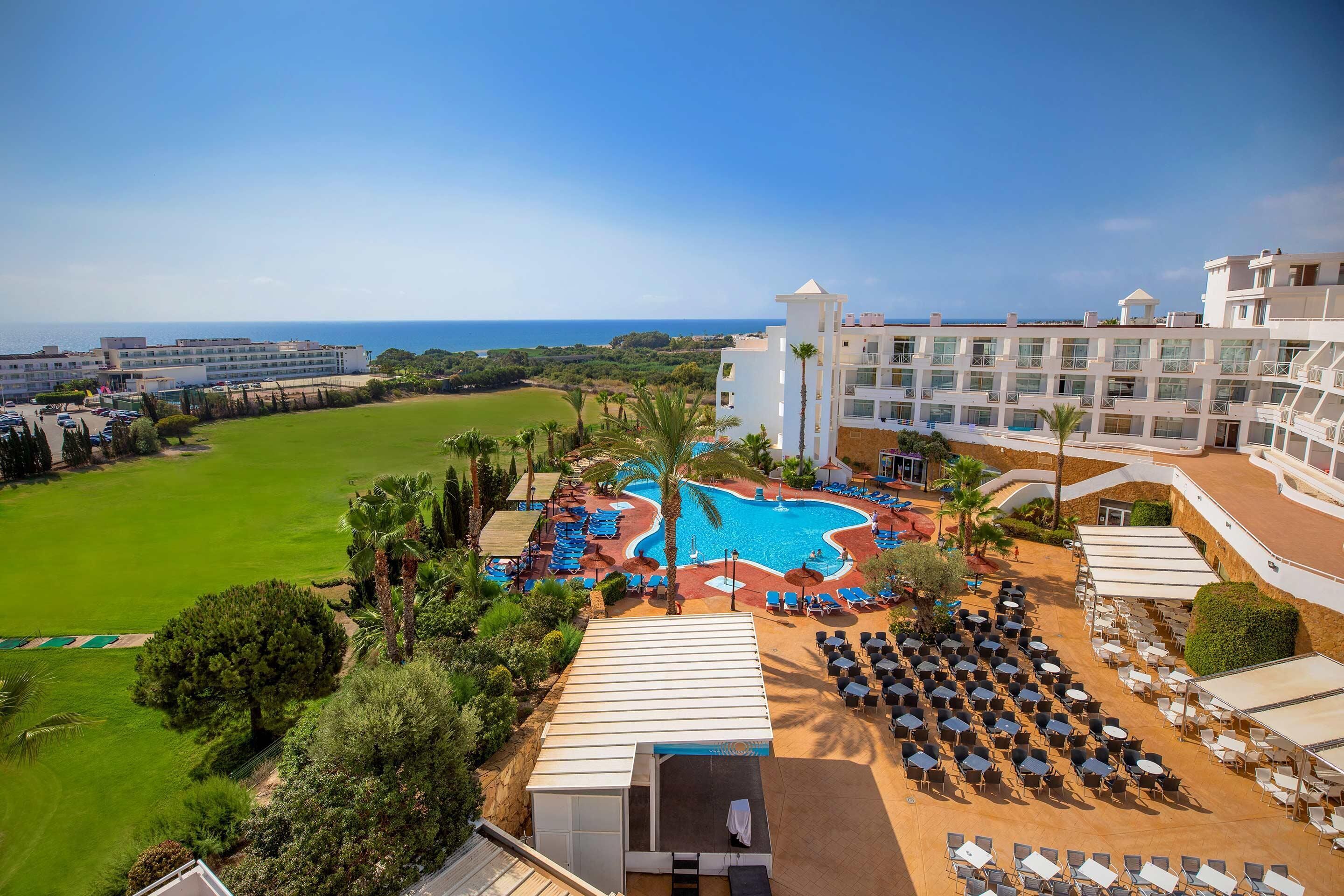A resort with a swimming pool, outdoor seating, and a view of the ocean.