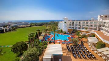 A resort with a swimming pool, outdoor seating, and a view of the ocean.