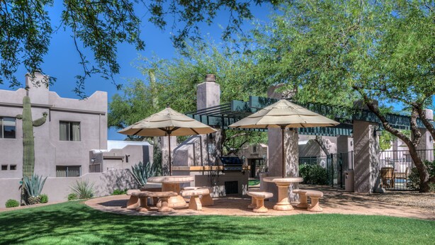 A patio area with stone tables and chairs, surrounded by a well-maintained lawn and cacti. - Villas of Cave Creek (Cave Creek)
