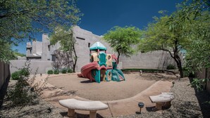 A playground with a slide and climbing structures, surrounded by a sandy area and benches. - Villas of Cave Creek (Cave Creek)