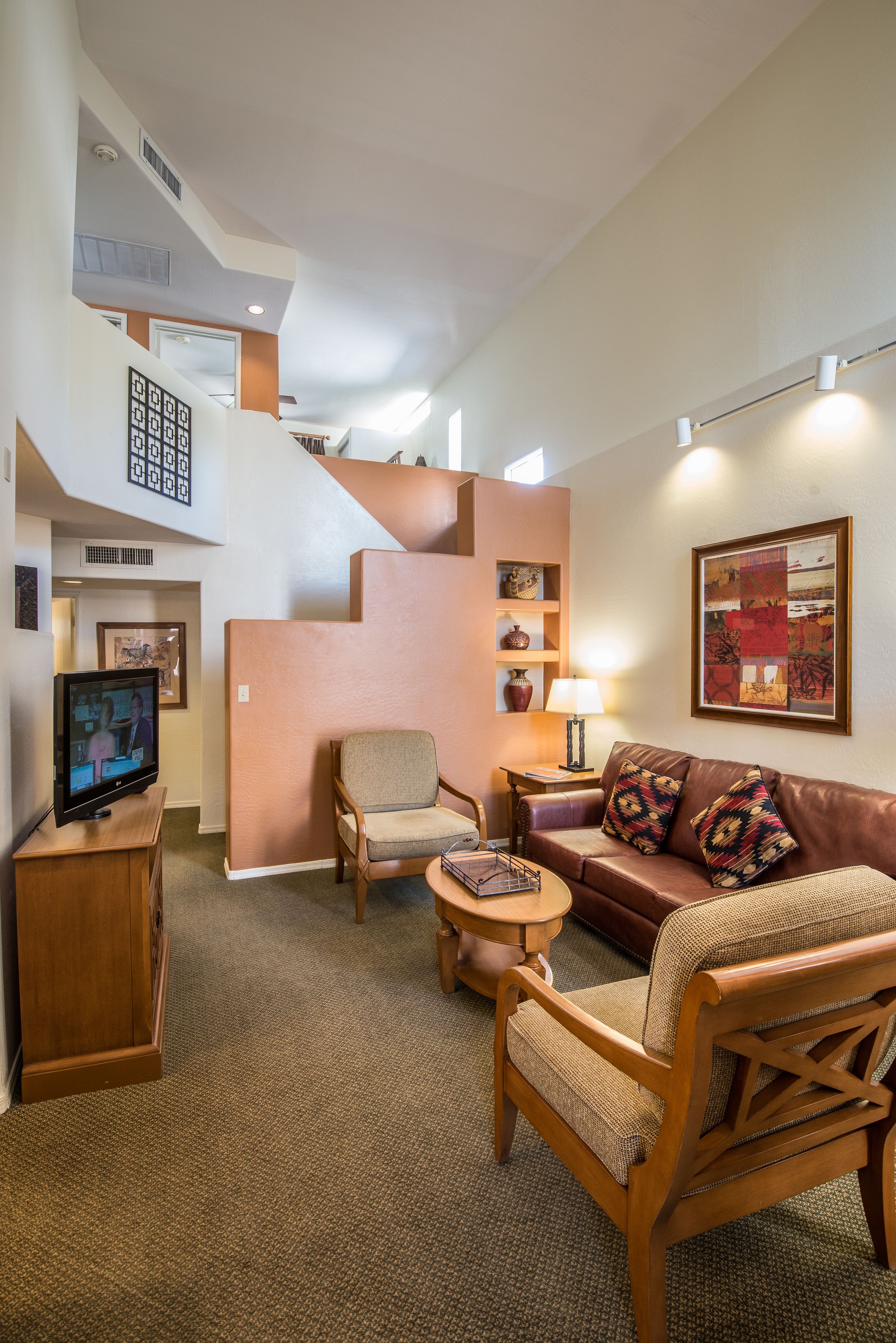 Una sala de estar moderna con una escalera, televisor, sofá y mesa de centro.